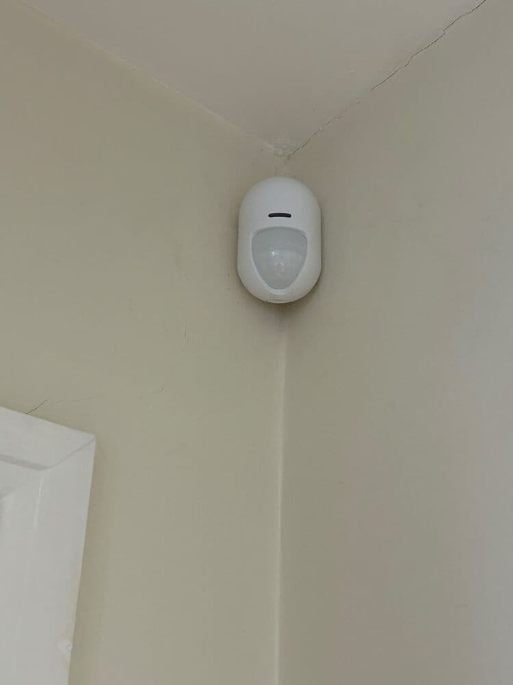 A wireless PIR movement sensor fitted in the corner of a room